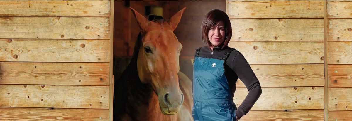 Ragazza che lavora in scuderia per cavalli indossando la pettorina uragan-tex